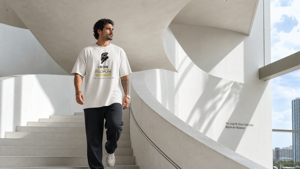 Wide-angle view of a man wearing the off-white "Iron Discipline" oversized t-shirt walking down concrete stairs at the Pérez Art Museum Miami.